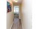 Hallway with light colored walls, wood-look tile flooring, and view of a bedroom with a floral bedspread at 3526 Overland Dr, Holiday, FL 34691