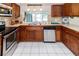 Functional kitchen with stainless appliances, warm wood cabinetry, and a bright window over the sink at 3526 Overland Dr, Holiday, FL 34691