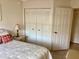 Bedroom showing a white door and closet with dark handles, tile floors, and a queen bed with side table at 4529 Whitton Way # 214, New Port Richey, FL 34653