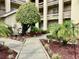 Landscaped walkway to the building with plants, trees and well maintained red mulch at 4529 Whitton Way # 214, New Port Richey, FL 34653