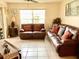 Inviting living room has comfortable leather seating, a large window and tile flooring at 4529 Whitton Way # 214, New Port Richey, FL 34653