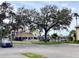 View of the community pool and the parking lot with mature trees in the area at 4529 Whitton Way # 214, New Port Richey, FL 34653