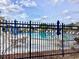 Community pool surrounded by a wrought iron fence, blue umbrellas, tables and chairs at 4529 Whitton Way # 214, New Port Richey, FL 34653