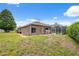 View of the back of the house with a lawn, screened-in pool enclosure, and blue skies at 6112 Kinlock Ave, Spring Hill, FL 34608