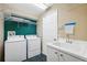 This laundry room includes a utility sink, storage shelves, and a washing machine at 6112 Kinlock Ave, Spring Hill, FL 34608