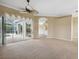 Spacious living room with neutral carpeting, ceiling fan, and sliding glass doors leading to screened pool at 6112 Kinlock Ave, Spring Hill, FL 34608