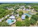 An aerial view of a community pool, tennis courts, and common area surrounded by lush landscape at 10910 May Apple Ct, Land O Lakes, FL 34638