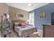 Bright bedroom featuring a decorative paisley bedspread, wicker headboard, and a sunlit window at 10910 May Apple Ct, Land O Lakes, FL 34638