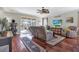 Open living room with hardwood floors, a ceiling fan, and a view of the screened-in pool area at 10910 May Apple Ct, Land O Lakes, FL 34638