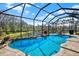 Stunning pool with a waterfall and scenic lake view, surrounded by a screened enclosure for privacy at 10910 May Apple Ct, Land O Lakes, FL 34638