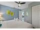 Bright bedroom featuring cool blue walls, a ceiling fan, closet space, and views to the main living area at 1101 N Betty Ln, Clearwater, FL 33755