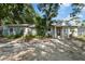 Charming single-story home with a red door, lush landscaping, and a gravel driveway at 1101 N Betty Ln, Clearwater, FL 33755