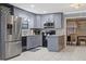 Stylish kitchen featuring gray cabinets, black appliances, and a herringbone backsplash, adjacent to a dining area at 1101 N Betty Ln, Clearwater, FL 33755
