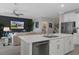 Open-concept living area with a kitchen island, comfortable seating, modern decor, and a large wall-mounted TV at 17026 Shell Bay Dr, Land O Lakes, FL 34638