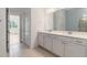 Bathroom featuring tiled floors, large mirrors, and white double vanity with ample storage space at 18629 Coastal Shore Ter, Land O Lakes, FL 34638