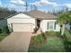 Charming one-story home featuring a brick driveway, two-car garage, manicured lawn, and decorative front door wreath at 18629 Coastal Shore Ter, Land O Lakes, FL 34638