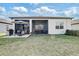 Backyard view of home with screened-in patio, outdoor grill and seating area, and lush green lawn at 18629 Coastal Shore Ter, Land O Lakes, FL 34638