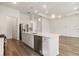 An open kitchen and living room, featuring an island, stainless appliances, and hardwood floors at 18629 Coastal Shore Ter, Land O Lakes, FL 34638