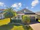 Lovely home featuring a lush green lawn, complemented by elegant landscaping and stately palm trees at 19504 Lily Pond Ct, Brooksville, FL 34601