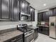 Modern kitchen features dark cabinetry, stainless steel appliances, and granite countertops at 19504 Lily Pond Ct, Brooksville, FL 34601
