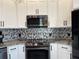 Modern kitchen with stainless steel appliances, white cabinets, and a unique backsplash design at 6734 Dali Ave # 205, Land O Lakes, FL 34637