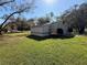 Sunny view of the detached garage with a large well-maintained lawn at 7090 Red Oak Loop, New Port Richey, FL 34654