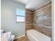 Bright bathroom featuring tiled shower and bathtub, complemented by a window for natural light at 12242 Greenwood St, Brooksville, FL 34613