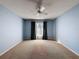 Spacious bedroom with carpet, a ceiling fan, a window with curtains, and light blue walls at 13103 Cypress Hill Dr # B2, Hudson, FL 34669