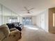 Bright living room featuring wall mirror, neutral carpet, ceiling fan and sliding doors to screened porch at 13103 Cypress Hill Dr # B2, Hudson, FL 34669