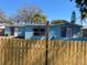 Charming single-story home with a bright blue exterior, red trim, and a well-maintained wooden fence at 1817 Dartmouth Dr, Holiday, FL 34691