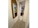 Hallway view leading to bathroom with neutral tile flooring and a decorative mirror at 1817 Dartmouth Dr, Holiday, FL 34691