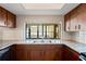 Bright kitchen with granite counters, wood cabinets, stainless steel sink, and view out to the lanai at 2013 Meredith Dr, Spring Hill, FL 34608