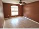 Bedroom showcasing brown walls, tile flooring, a ceiling fan, and a large window bringing in natural light at 355 Royal Palm Way, Spring Hill, FL 34608