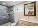 Elegant bathroom featuring a luxurious shower with marble-like tile and a vanity with a framed mirror at 3736 Sail Dr, New Port Richey, FL 34652