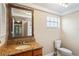 Bathroom featuring a granite-look vanity with a sink, a toilet, and a framed mirror at 3736 Sail Dr, New Port Richey, FL 34652