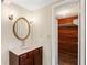 Bathroom featuring a wooden vanity with a sink, a round mirror, and a view into the wood-paneled closet at 3736 Sail Dr, New Port Richey, FL 34652