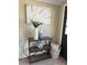 Decorated entryway with a modern metal rack, decorative vases, greenery and a leaf-themed painting for a cozy, welcoming atmosphere at 3736 Sail Dr, New Port Richey, FL 34652