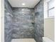 Shower featuring marble-like tile, rainfall shower head, handheld sprayer, and a built-in shelf at 3736 Sail Dr, New Port Richey, FL 34652