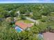 Expansive aerial view showcasing a screened pool, lush green surroundings, and neighborhood streets at 4603 Lake In The Woods Dr, Spring Hill, FL 34607