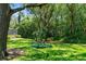 Lush backyard featuring a charming blue swing hanging from a mature tree, offering a tranquil retreat at 4603 Lake In The Woods Dr, Spring Hill, FL 34607