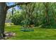 Backyard featuring a swing, lush green grass, and mature trees that offer shade and privacy at 4603 Lake In The Woods Dr, Spring Hill, FL 34607