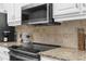 Close-up of a modern kitchen with stainless steel appliances, granite countertops, and tile backsplash at 4603 Lake In The Woods Dr, Spring Hill, FL 34607