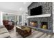 Living room featuring stone fireplace, tv and sliders that lead to a screened in outdoor patio at 4603 Lake In The Woods Dr, Spring Hill, FL 34607