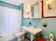 Vintage blue tiled bathroom with a pedestal sink, toilet, and a shower with a white curtain at 4929 N River Shore Dr # A, Tampa, FL 33603