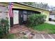 A front exterior view of the charming home with an American flag waving beside the door at 8302 Clover Hill Loop, Hudson, FL 34667