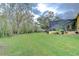 Expansive backyard featuring a screened-in pool enclosure and large green lawn area, framed by mature trees and landscaping at 1031 Pomme De Pin Ln, New Port Richey, FL 34655