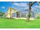 Spacious backyard featuring a screened-in pool, lush green grass, and mature trees for outdoor enjoyment at 1031 Pomme De Pin Ln, New Port Richey, FL 34655