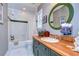 Bathroom with tiled shower, decorative mirror, and wooden accents, offering a cozy and stylish space at 1031 Pomme De Pin Ln, New Port Richey, FL 34655