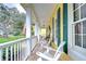Relaxing front porch featuring white rocking chairs, views of the lush landscaping, and an American flag at 1031 Pomme De Pin Ln, New Port Richey, FL 34655