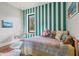 Cozy bedroom with green and white striped walls, a hanging chair, and a colorful quilt at 11151 Lu Wista Ln, Brooksville, FL 34601